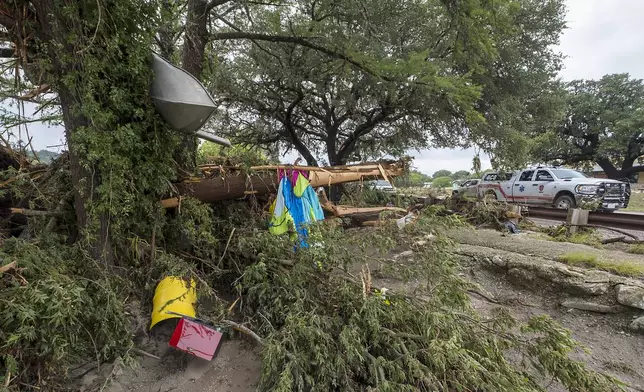 A bent canoe and debris are stuck high in a tree along the banks of the Guadalupe River on Saturday, July 5, 2025, in Ingram, Texas. (AP Photo/Rodolfo Gonzalez)