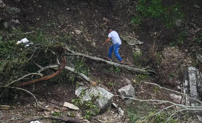 A man combs through the banks of the Guadalupe River near Camp Mystic after a flash flood swept through the area Saturday, July 5, 2025, in Hunt, Texas. (AP Photo/Julio Cortez)