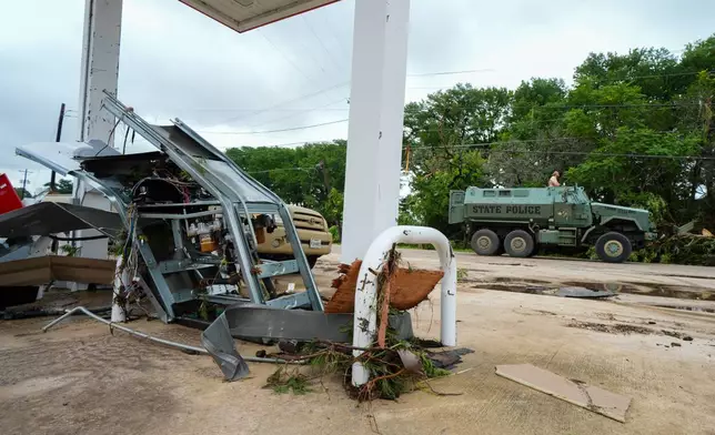 A Texas State Police armored vehicle rolls by a damaged gas pump at a gas station along the Guadalupe River after a flash flood swept through the area Saturday, July 5, 2025, in Hunt, Texas. (AP Photo/Julio Cortez)