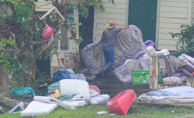A person removes bedding from sleeping quarters at Camp Mystic along the banks of the Guadalupe River after a flash flood swept through the area Sunday, July 6, 2025, in Hunt, Texas. (AP Photo/Julio Cortez)