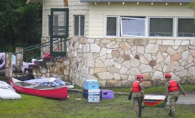 Military personnel return a camp trunk salvaged from down river to Camp Mystic along the Guadalupe River after a flash flood swept through the area Sunday, July 6, 2025, in Hunt, Texas. (AP Photo/Julio Cortez)
