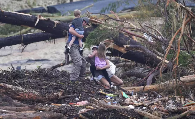 A woman falls while climbing with others over debris on a bridge atop the Guadalupe River after a flash flood swept through the area Saturday, July 5, 2025, in Ingram, Texas. (AP Photo/Julio Cortez)