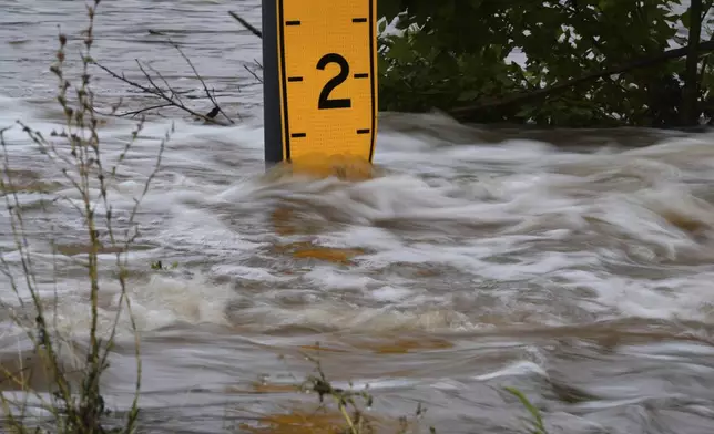 A flood gauge marks the height of water flowing over a farm-to-market road near Kerrville, Texas, on Friday, July 4, 2025. (AP Photo/Eric Gay)