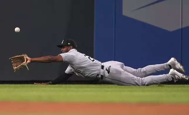 Chicago White Sox left fielder Michael A. Taylor dives for a double off the bat of Colorado Rockies' Yanquiel Fernández in the seventh inning of a baseball game Saturday, July 5, 2025, in Denver. (AP Photo/David Zalubowski)