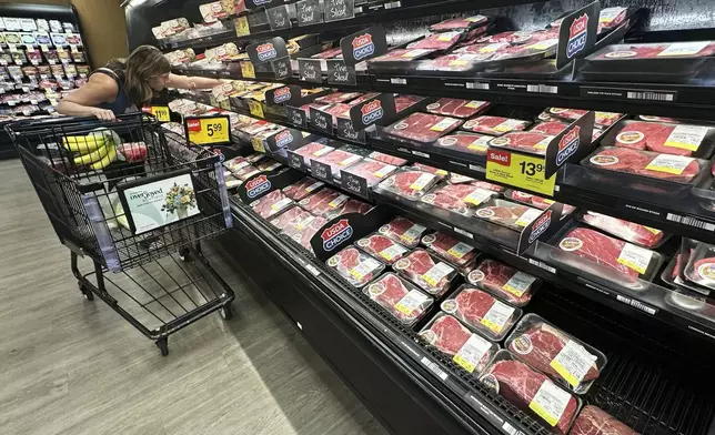A shopper compares beef prices at a grocery store in Mount Prospect, Ill., Thursday, July 17, 2025. (AP Photo/Nam Y. Huh)