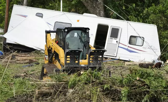 A person moves debris at Guadalupe Keys Resort, an RV park in Center Point, Texas, after flooding, Monday, July 7, 2025. (AP Photo/Ashley Landis)