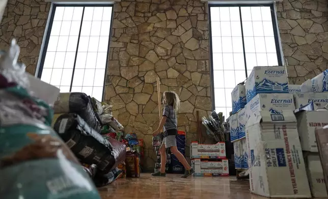 A child helps volunteers organize donations for victims of flash flooding in Texas inside the gym at Center Point Elementary in Center Point, Texas, Monday, July 7, 2025. (AP Photo/Ashley Landis)