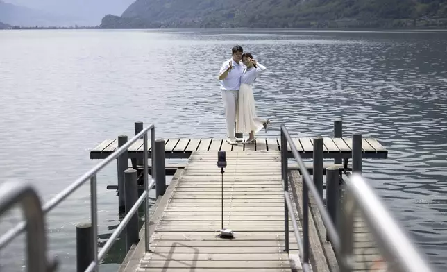 Korean visitors take pictures on the pier at Lake Brienz in Iseltwald, Switzerland, Sunday, May 21, 2023. (Peter Klaunzer/Keystone via AP)