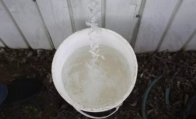 Theo Gantos pours water from his spigot in the North Morris Estates mobile home park, Thursday, April 24, 2025, in Mount Morris Township, Mich. (AP Photo/Carlos Osorio)