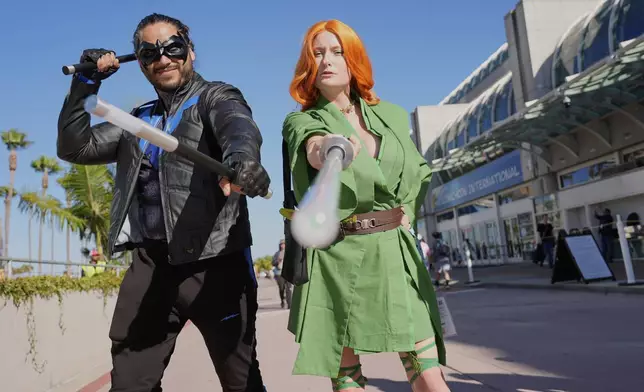 Ivan Martinez, left, dressed as "Nightwing," and Jade Stone, dressed as "Poison Ivy Jedi," pose for a photo before the 2025 Comic-Con International Preview Night on Wednesday, July 23, 2025, in San Diego. (AP Photo/Chris Pizzello)