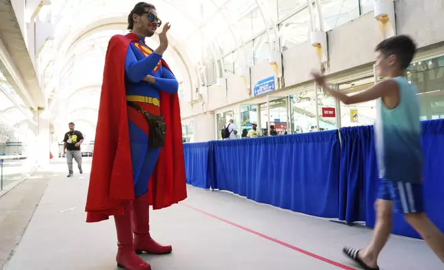 Comic-Con volunteer Chris Perry, left, dressed as Superman, waves to a young attendee before the 2025 Comic-Con International Preview Night on Wednesday, July 23, 2025, in San Diego. (AP Photo/Chris Pizzello)