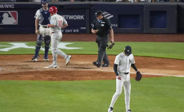 New York Yankees pitcher Luke Weaver, right, looks down as Philadelphia Phillies' J.T. Realmuto reaches home plate after hitting a three-run home run during the seventh inning of a baseball game Friday, July 25, 2025, in New York. (AP Photo/Frank Franklin II)