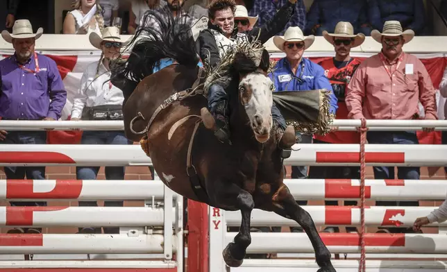 Cooper Cooke, of Idaho, rides Disco Party to win the bareback rodeo final at the Calgary Stampede in Calgary, Alberta, Sunday, July 13, 2025. (Jeff McIntosh/The Canadian Press via AP)