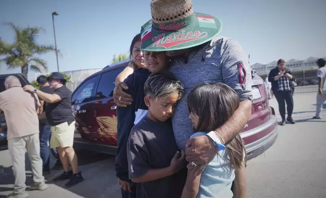 People embrace outside of Glass House Farms, a day after an immigration raid on the facility, on Friday, July 11, 2025, in Camarillo, Calif. (AP Photo/Damian Dovarganes)