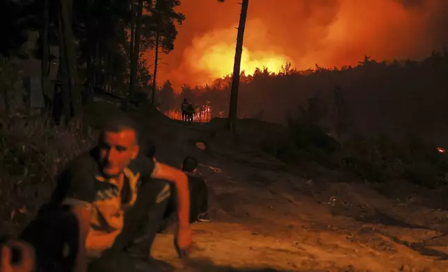 Syrian Civil Defense teams and volunteers battle wildfire flames for the tenth consecutive day near the town of Kasab, in Syria's Latakia countryside, early Saturday, July 12, 2025. (AP Photo/Ghaith Alsayed)