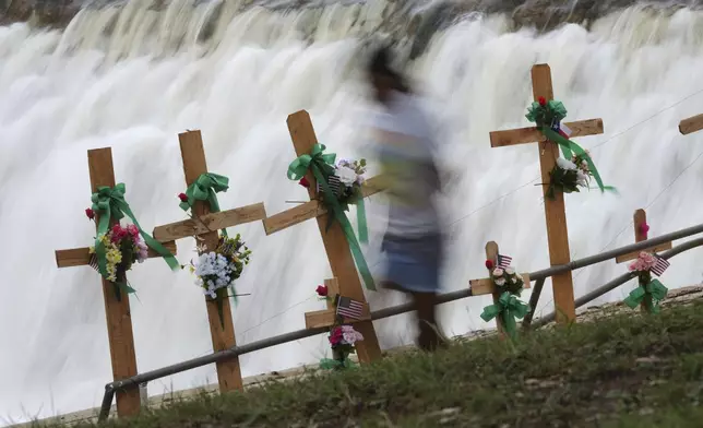 A young girl runs past crosses at a make-shift memorial honoring flood victims, Sunday, July 13, 2025, in Kerrville, Texas. (AP Photo/Eric Gay)