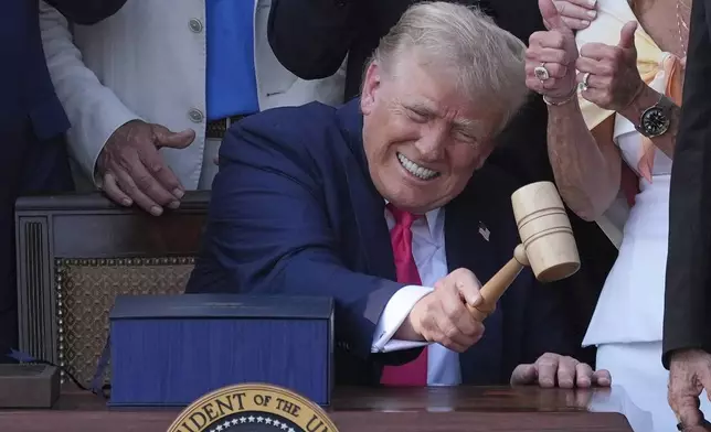 President Donald Trump bangs a gavel presented to him by House Speaker Mike Johnson of La., after he signed his signature bill of tax breaks and spending cuts at the White House, Friday, July 4, 2025, in Washington. (AP Photo/Evan Vucci)