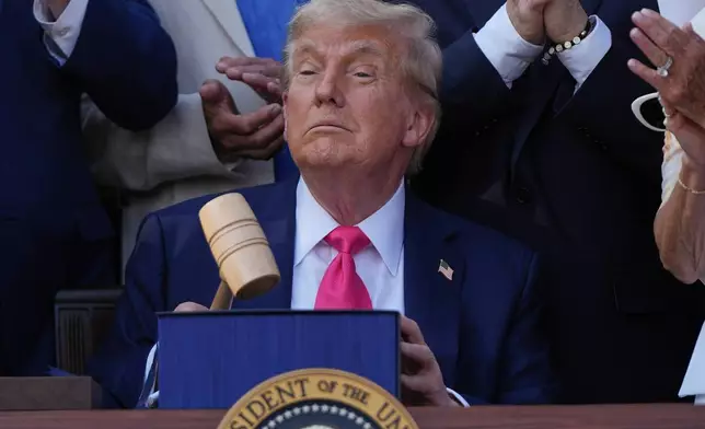 President Donald Trump holds a gavel after he signed his signature bill of tax breaks and spending cuts at the White House, Friday, July 4, 2025, in Washington, surrounded by members of Congress. (AP Photo/Julia Demaree Nikhinson)