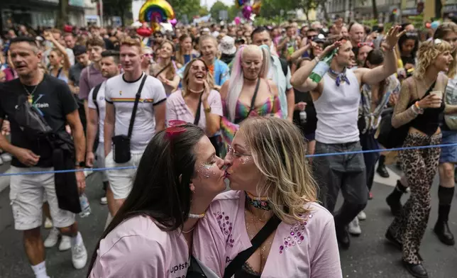 Two women kiss as they take part in the LGBTQ annual pride march in Berlin, Germany, Saturday, July 26, 2025. (AP Photo/Ebrahim Noroozi)