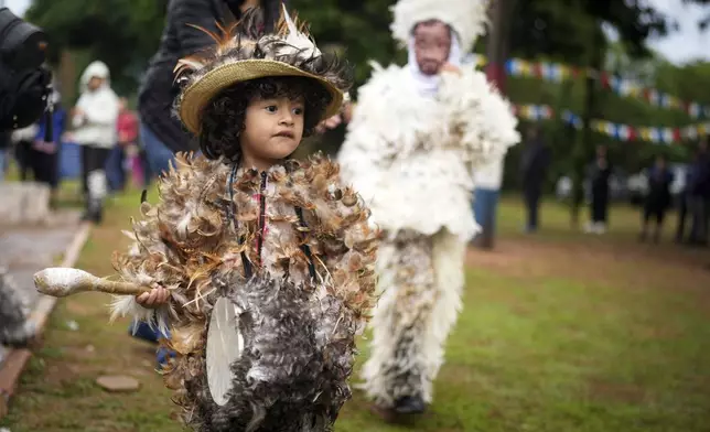 A child dressed in a feather costume plays a drum after attending a Mass celebrating Saint Francisco Solano, in Emboscada, Paraguay, Thursday, July 24, 2025. Hundreds of Catholic parishioners in Paraguay don bird-like costumes and parade down the streets to honor the 16th century saint said to possess miraculous powers. (AP Photo/Jorge Saenz)