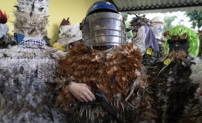 A parishioner dressed in a feather costume and a riot police mask poses for a photo during a Mass celebrating Saint Francisco Solano, in Emboscada, Paraguay, Thursday, July 24, 2025. Hundreds of Catholic parishioners in Paraguay don bird-like costumes and parade down the streets to honor the 16th century saint said to possess miraculous powers. (AP Photo/Jorge Saenz)