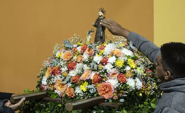 A man touches a statue of San Francisco Solano after attending a Mass celebrating Saint Francisco Solano, in Emboscada, Paraguay, Thursday, July 24, 2025. Hundreds of Catholic parishioners in Paraguay don bird-like costumes and parade down the streets to honor the 16th century saint said to possess miraculous powers. (AP Photo/Jorge Saenz)