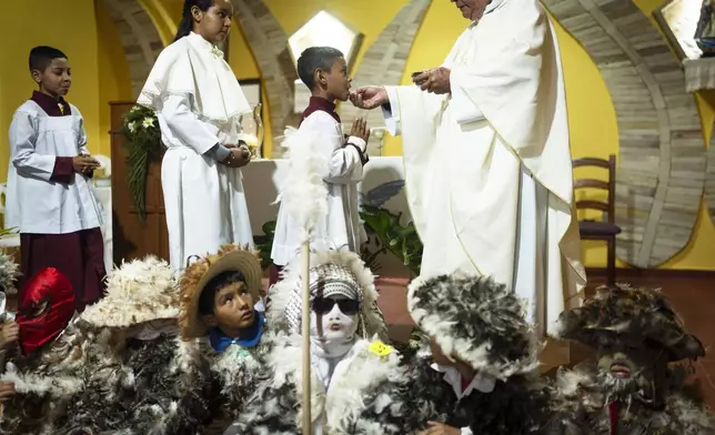 An altar server receives communion during a Mass celebrating Saint Francisco Solano, in Emboscada, Paraguay, Thursday, July 24, 2025. Hundreds of Catholic parishioners in Paraguay don bird-like costumes and parade down the streets to honor the 16th century saint said to possess miraculous powers. (AP Photo/Jorge Saenz)