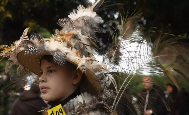 Lucas Darrel poses for a photo in his feather costume during a Mass celebrating Saint Francisco Solano, in Emboscada, Paraguay, Thursday, July 24, 2025. Hundreds of Catholic parishioners in Paraguay don bird-like costumes and parade down the streets to honor the 16th century saint said to possess miraculous powers. (AP Photo/Jorge Saenz)