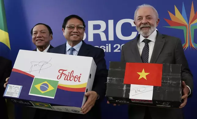 Brazilian President Luiz Inacio Lula da Silva, right, holding an empty box representing Vietnamese fish, and Vietnam's Prime Minister Pham Minh Chinh, holding an empty box representing Brazilian beef, pose for photos after signing a bilateral trade agreement, ahead of the upcoming 17th annual BRICS summit in Rio de Janeiro, Saturday, July 5, 2025. (AP Photo/Bruna Prado)