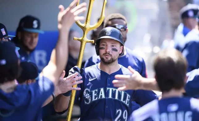 Seattle Mariners' Cal Raleigh is greeted by teammates after hitting a home run during the seventh inning of a baseball game against the Los Angeles Angels Sunday, July 27, 2025, in Anaheim, Calif. (AP Photo/William Liang)