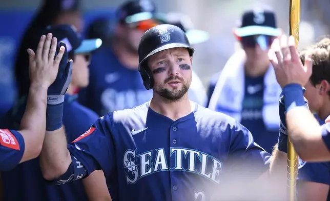 Seattle Mariners' Cal Raleigh is greeted by teammates after hitting a home run during the seventh inning of a baseball game against the Los Angeles Angels, Sunday, July 27, 2025, in Anaheim, Calif. (AP Photo/William Liang)