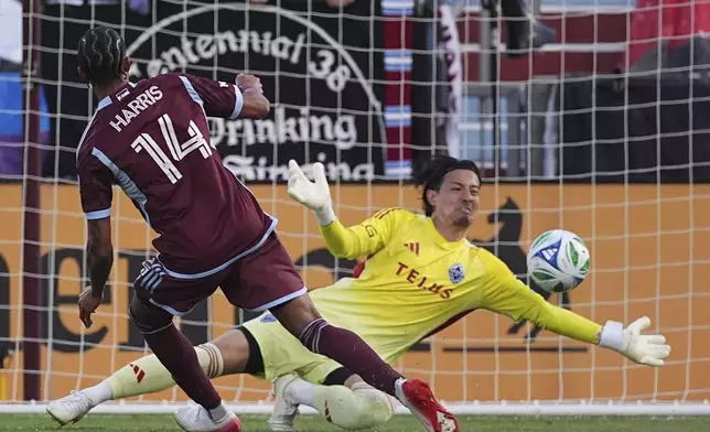 Colorado Rapids forward Calvin Harris (14) scores past Vancouver Whitecaps goalkeeper Yohei Takaoka, right, in the first half of an MLS soccer match Saturday, July 12, 2025, in Commerce City, Colo. (AP Photo/David Zalubowski)