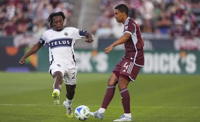 Colorado Rapids defender Reggie Cannon, right, passes the ball as Vancouver Whitecaps midfielder Jean-Claude Ngando, left, defends in the first half of an MLS soccer match Saturday, July 12, 2025, in Commerce City, Colo. (AP Photo/David Zalubowski)