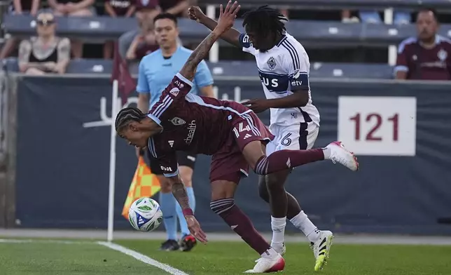 Colorado Rapids forward Calvin Harris (14) and Vancouver Whitecaps midfielder Jean-Claude Ngando, right, fight for control of the ball in the first half of an MLS soccer match Saturday, July 12, 2025, in Commerce City, Colo. (AP Photo/David Zalubowski)