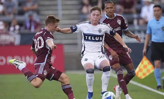 Vancouver Whitecaps defender Tate Johnson, center, moves the ball between Colorado Rapids midfielder Connor Ronan, left, and forward Calvin Harris, right, in the first half of an MLS soccer match Saturday, July 12, 2025, in Commerce City, Colo. (AP Photo/David Zalubowski)