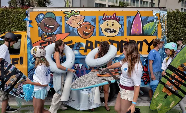 Members of the Southern California Surf Academy prepare to participate in the Independence Day Parade in Santa Monica, Calif. on Friday, July 4, 2025. (AP Photo/Richard Vogel)