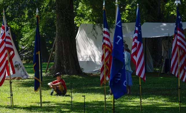 A child looks on at a display of flags significant to American history during a Independence Day observation at Locust Grove, a National Historic Landmark, Friday, July 4, 2025, in Louisville, Ky. (AP Photo/Jon Cherry)
