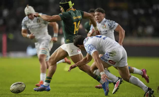 South Africa's Edwill van der Merwe, centre, kicks the ball to score a try as Italy's Alessandro Garbisi try during a rugby championship test match between South Africa and Italy, at the Nelson Mandela Bay stadium in Gqeberha, South Africa, Saturday, July 12, 2025. (AP Photo/Themba Hadebe)
