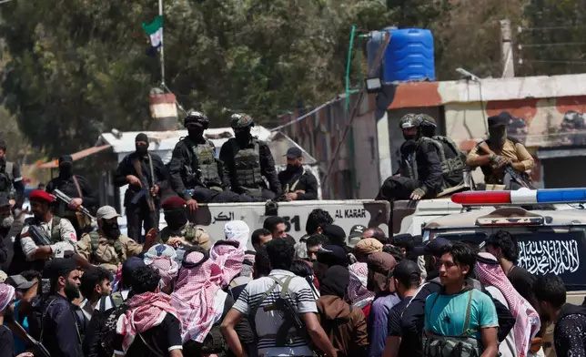 Syrian government security forces block Bedouin fighters, foreground, from entering Sweida province, in Busra al-Harir village, southern Syria, Sunday, July 20, 2025. (AP Photo/Omar Sanadiki)