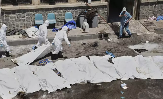 Morgue workers place the bodies of unidentified people killed during clashes between Bedouin clans and Druze militias, into plastic bags outside the National Hospital in Sweida, Syria, Monday, July 21, 2025. (AP Photo/Fahd Kiwan)