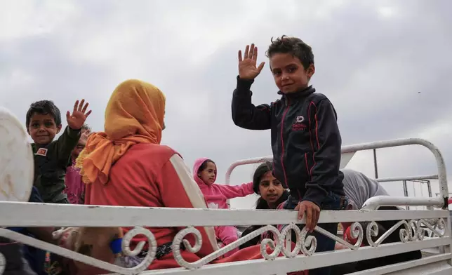 Syrian Bedouin families gesture as they ride in a convoy led by Red Crescent vehicles in Busra al-Harir, heading to Daraa after being evacuated from Sweida following more than a week of violent clashes, Monday, July 21, 2025. (AP Photo/Malek Khattab)