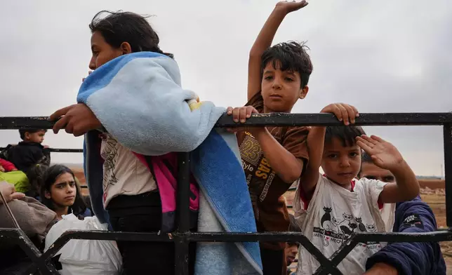 Syrian Bedouin families gesture as they ride in a convoy led by Red Crescent vehicles in Busra al-Harir, heading to Daraa after being evacuated from Sweida following more than a week of violent clashes, Monday, July 21, 2025. (AP Photo/Malek Khattab)