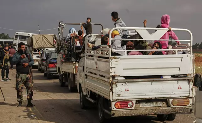 Syrian Bedouin families ride in the back of trucks carrying their belongings, in a convoy led by Red Crescent vehicles in Busra al-Harir, heading to Daraa after being evacuated from Sweida following more than a week of violent clashes, Monday, July 21, 2025. (AP Photo/Malek Khattab)
