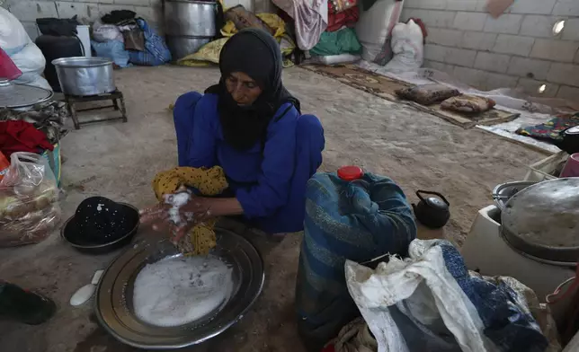 A displaced Bedouin woman washes clothes inside a shelter after fleeing her home due to clashes between Bedouin clans and Druze militias, in Busra al-Harir village, southern Syria, Sunday, July 20, 2025. (AP Photo/Omar Sanadiki)