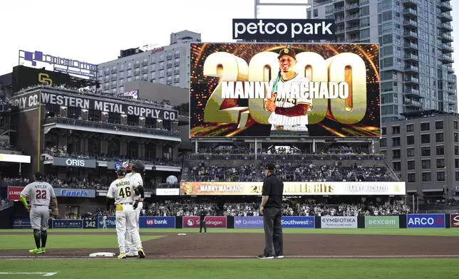 San Diego Padres' Manny Machado, third from left, reacts after hitting a single, his 2000th career hit, during the fourth inning of a baseball game against the Arizona Diamondbacks, Monday, July 7, 2025, in San Diego. (AP Photo/Orlando Ramirez)