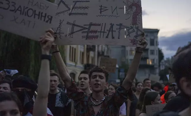 Man chants and holds banner reading "Where are you and where are the people?" during a protest against a law targeting anti-corruption institutions in central Kyiv, Ukraine, Tuesday, July 22, 2025. (AP Photo/Alex Babenko)