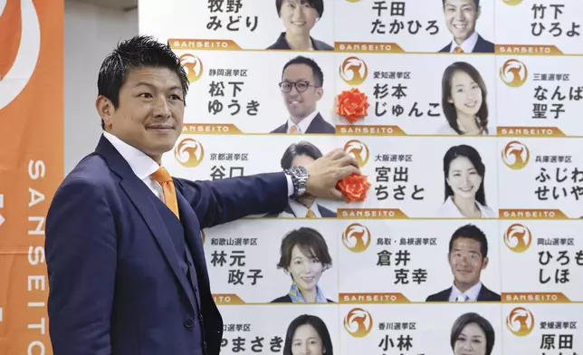 Sohei Kamiya, leader of Japan's far-right populist Sanseito party, places a red paper rose on the name of an elected candidate, in Tokyo, Sunday, July 20, 2025. (Kyodo News via AP)
