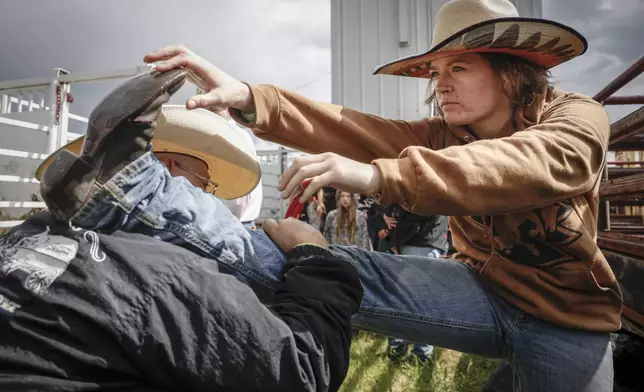 Emma Eastwood, from Lacombe, Alberta, stretches before competing in women's ranch bronc during rodeo action in Crossfield, Alberta, Saturday, June 14, 2025. (Jeff McIntosh/The Canadian Press via AP)