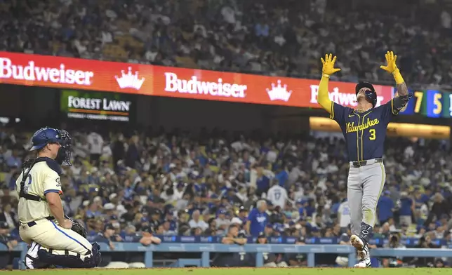 Milwaukee Brewers' Joey Ortiz, right, gestures as he scores after hitting a solo home run as Los Angeles Dodgers catcher Will Smith watches during the eighth inning of a baseball game Saturday, July 19, 2025, in Los Angeles. (AP Photo/Mark J. Terrill)