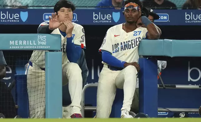 Los Angeles Dodgers' Shohei Ohtani, left, and Esteury Ruiz watch from the dugout during the ninth inning of a baseball game against the Milwaukee Brewers, Saturday, July 19, 2025, in Los Angeles. (AP Photo/Mark J. Terrill)